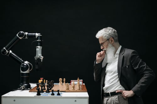 Brazo robotico juega ajedrez con persona mayor